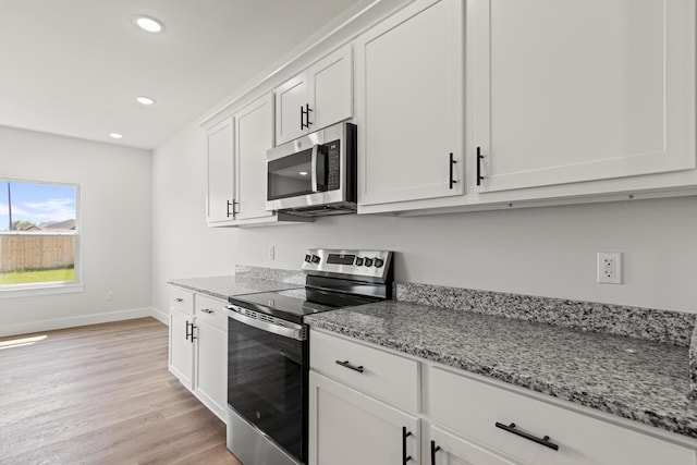 kitchen featuring light wood finished floors, baseboards, light stone countertops, and appliances with stainless steel finishes