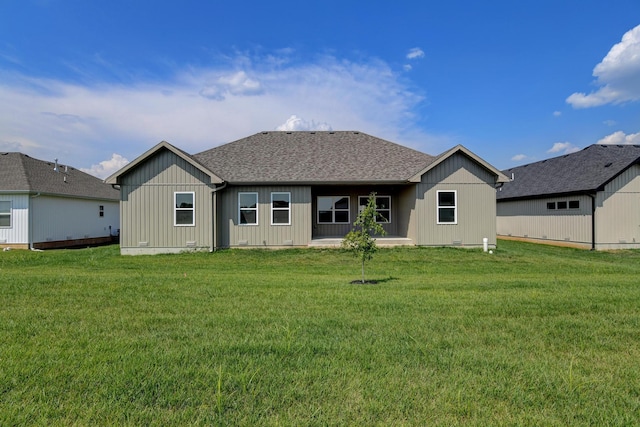 back of property with board and batten siding, a yard, and roof with shingles