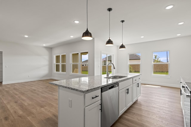 kitchen featuring stainless steel dishwasher, a sink, light wood-type flooring, and baseboards