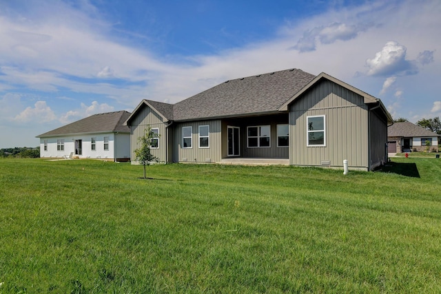 rear view of property featuring a patio area, roof with shingles, a yard, and board and batten siding