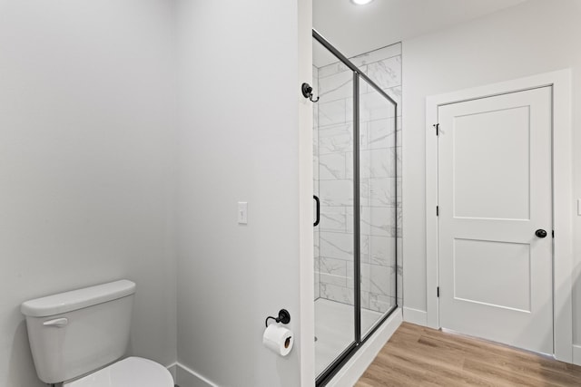 full bathroom featuring baseboards, toilet, wood finished floors, and a stall shower