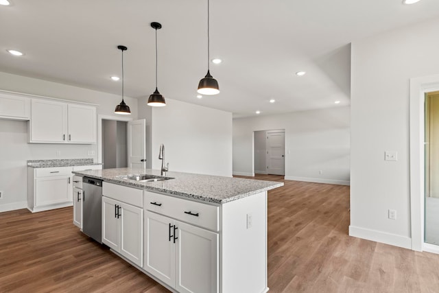 kitchen featuring light stone counters, an island with sink, sink, white cabinetry, and light wood-type flooring