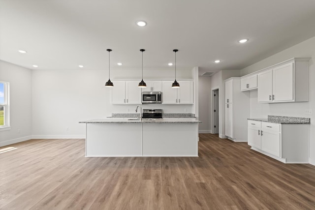 kitchen with white cabinets, stainless steel appliances, wood finished floors, and baseboards