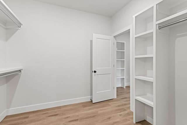 walk in closet with light wood finished floors