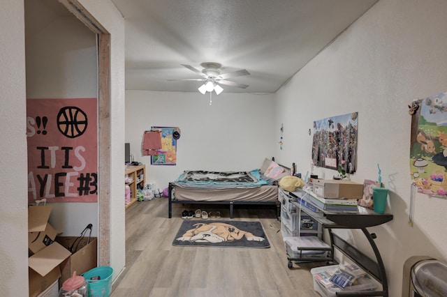 bedroom with ceiling fan, hardwood / wood-style flooring, and a textured ceiling