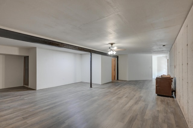 basement featuring hardwood / wood-style flooring, wooden walls, and ceiling fan