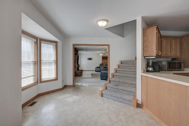 staircase featuring ceiling fan and concrete floors