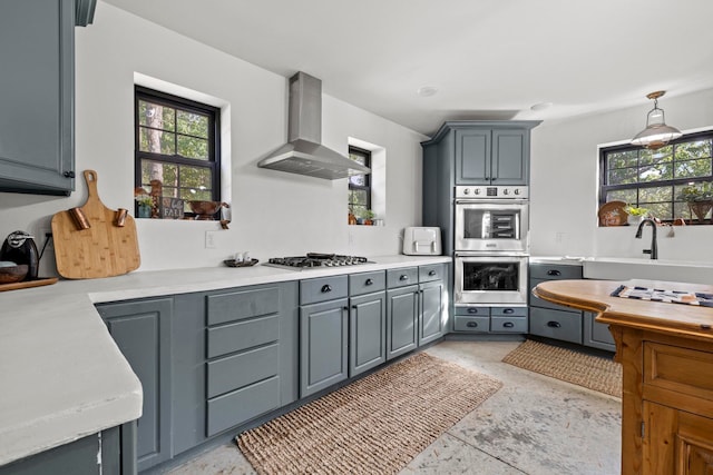 kitchen with wall chimney exhaust hood, appliances with stainless steel finishes, sink, and gray cabinetry