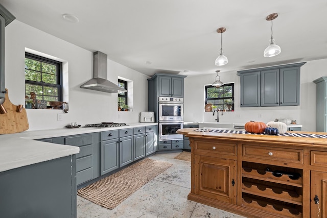 kitchen with hanging light fixtures, extractor fan, gray cabinets, and appliances with stainless steel finishes