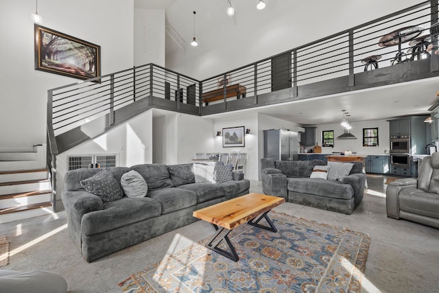 living room featuring a towering ceiling and concrete flooring