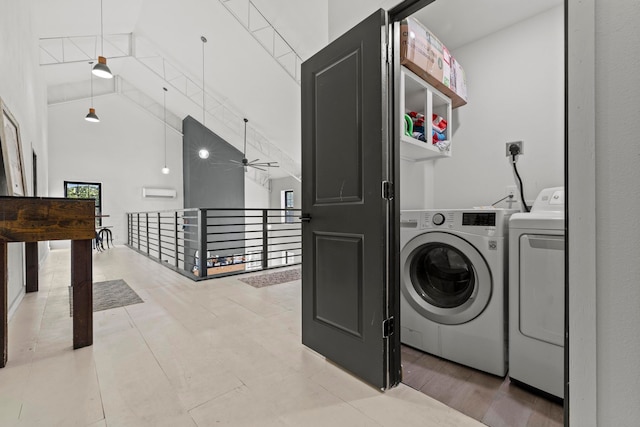 laundry area with a towering ceiling, washing machine and dryer, and ceiling fan