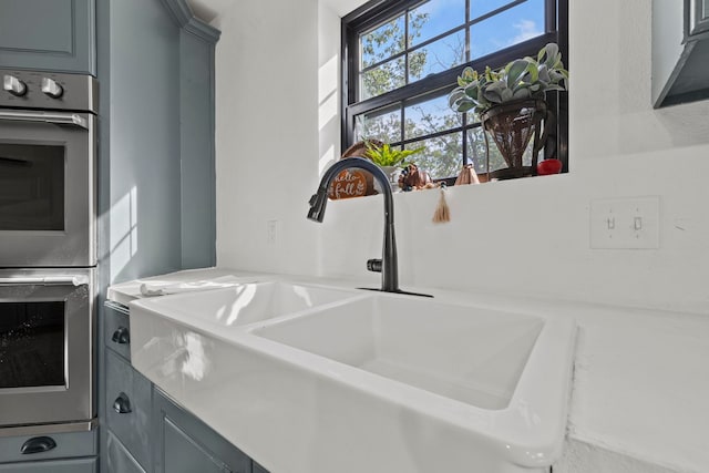 details featuring gray cabinetry, stainless steel double oven, and sink