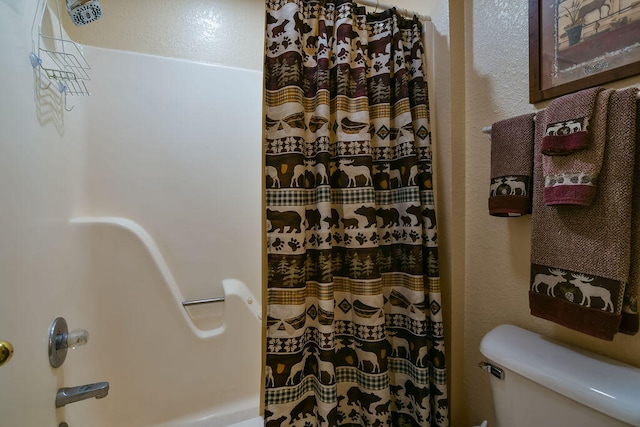 bathroom featuring toilet and curtained shower