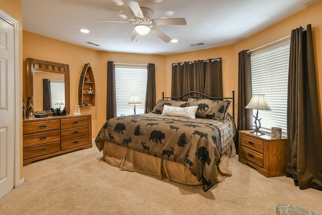 bedroom with ceiling fan, light carpet, and multiple windows