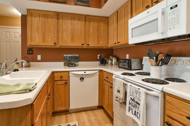 kitchen featuring light wood-type flooring, white appliances, and sink