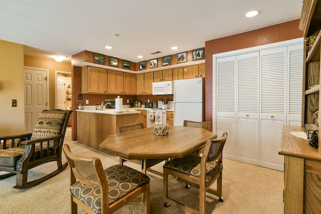 dining space featuring light colored carpet, sink, and a textured ceiling