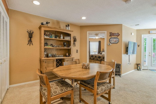 dining space with a textured ceiling, ceiling fan, and light colored carpet