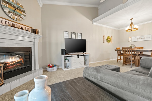 carpeted living room featuring crown molding, a high ceiling, a chandelier, and a tiled fireplace