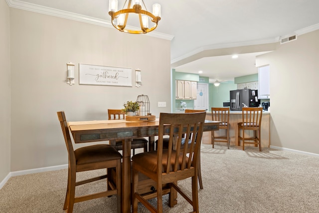 dining room with ornamental molding, light colored carpet, and an inviting chandelier