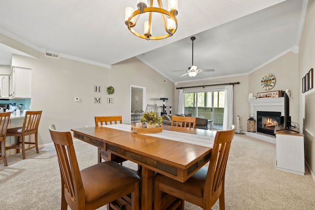 carpeted dining room with ceiling fan with notable chandelier, crown molding, and vaulted ceiling