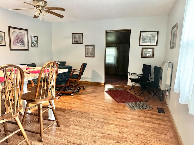 dining room featuring ceiling fan, light hardwood / wood-style floors, and a textured ceiling