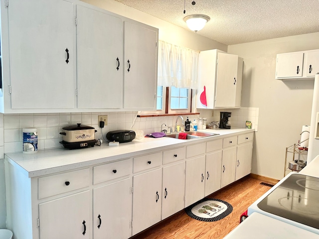 kitchen featuring hardwood / wood-style floors, white cabinetry, sink, and tasteful backsplash