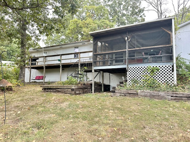 rear view of house featuring a sunroom, a deck, and a lawn