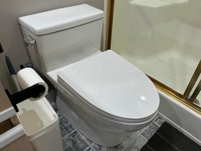 bathroom featuring toilet, shower / washtub combination, and tile patterned floors