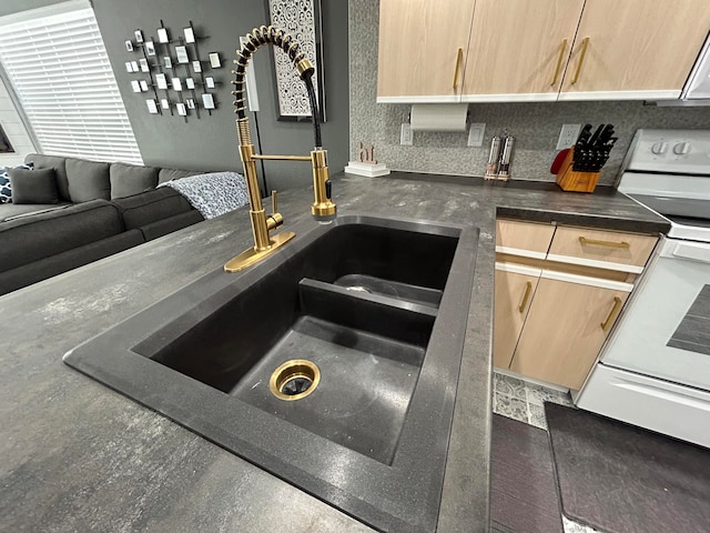 kitchen with light brown cabinets, white electric range, and sink