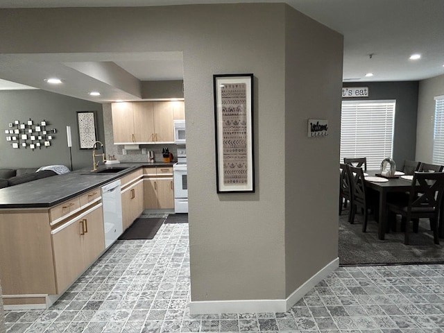 kitchen with white appliances, kitchen peninsula, light brown cabinets, and sink