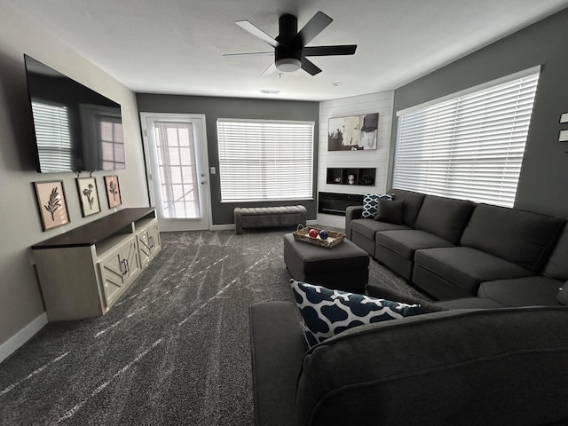 living room featuring ceiling fan and dark colored carpet