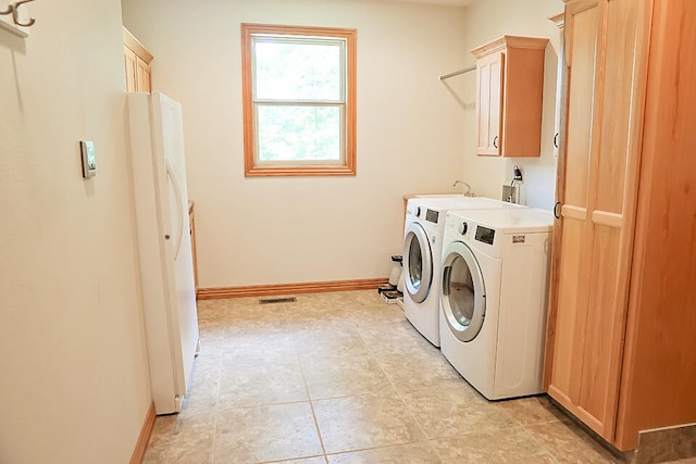 clothes washing area with light tile patterned flooring, cabinets, and washer and clothes dryer