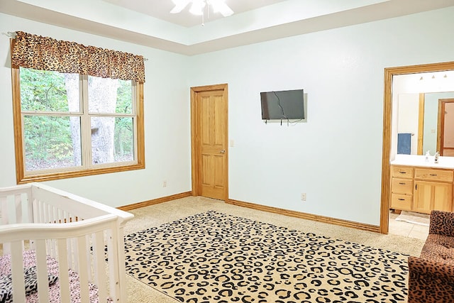 bedroom with a nursery area, ceiling fan, and ensuite bath