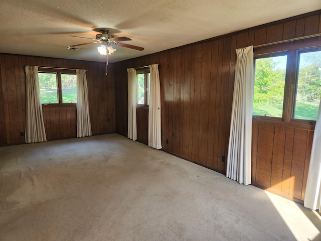 28409 Bali Rd, Warsaw, MO 65355 - carpeted empty room with wood walls, a ceiling fan, visible vents, and a textured ceiling