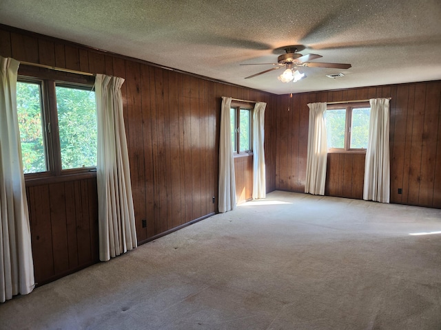 28409 Bali Rd, Warsaw, MO 65355 - carpeted empty room featuring wooden walls, visible vents, a textured ceiling, and a ceiling fan