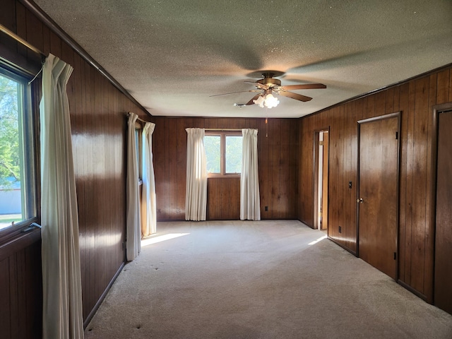 28409 Bali Rd, Warsaw, MO 65355 - unfurnished bedroom featuring wooden walls, ceiling fan, light colored carpet, and a textured ceiling