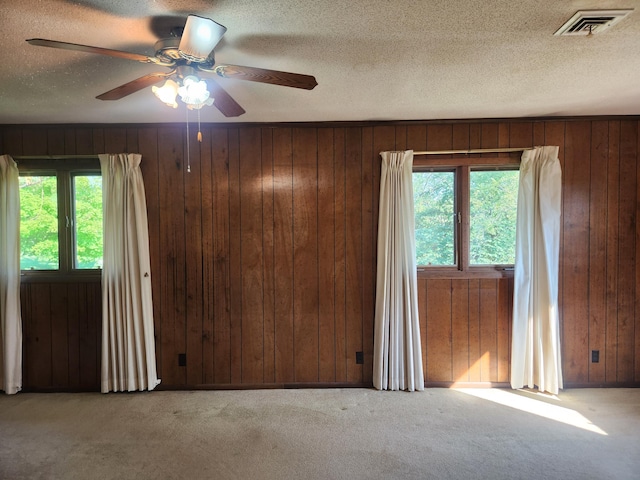 28409 Bali Rd, Warsaw, MO 65355 - spare room with a textured ceiling, a ceiling fan, visible vents, carpet floors, and wood walls