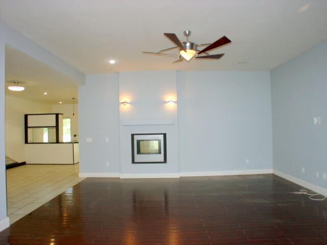 unfurnished living room with a fireplace, wood-type flooring, and ceiling fan