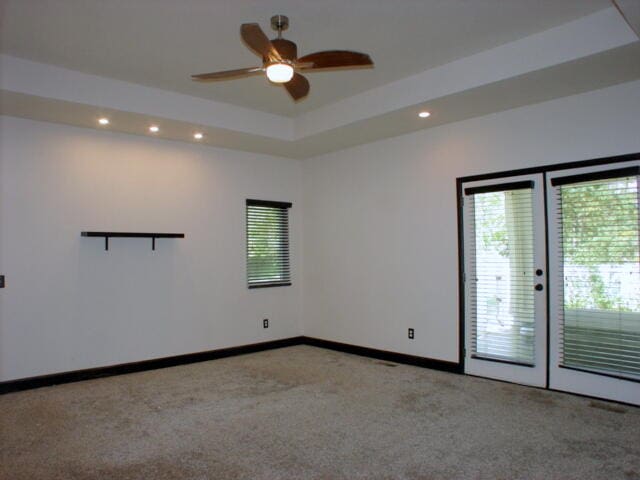 unfurnished room featuring ceiling fan, a tray ceiling, french doors, and carpet