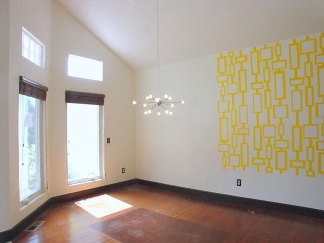 unfurnished room with dark wood-type flooring, high vaulted ceiling, an inviting chandelier, and a healthy amount of sunlight