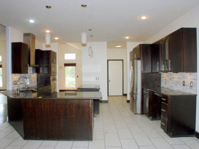 kitchen with stainless steel refrigerator, pendant lighting, ventilation hood, sink, and kitchen peninsula