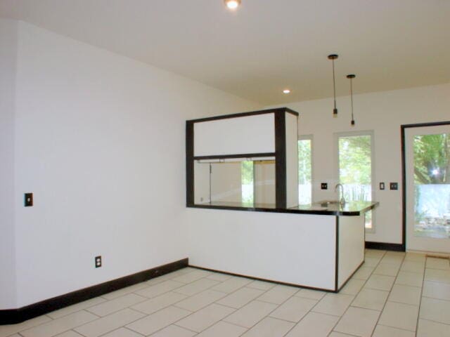 kitchen featuring kitchen peninsula, hanging light fixtures, light tile patterned floors, and white cabinetry