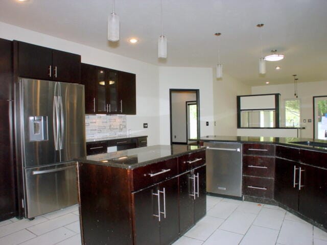 kitchen with light tile patterned flooring, pendant lighting, backsplash, appliances with stainless steel finishes, and a center island