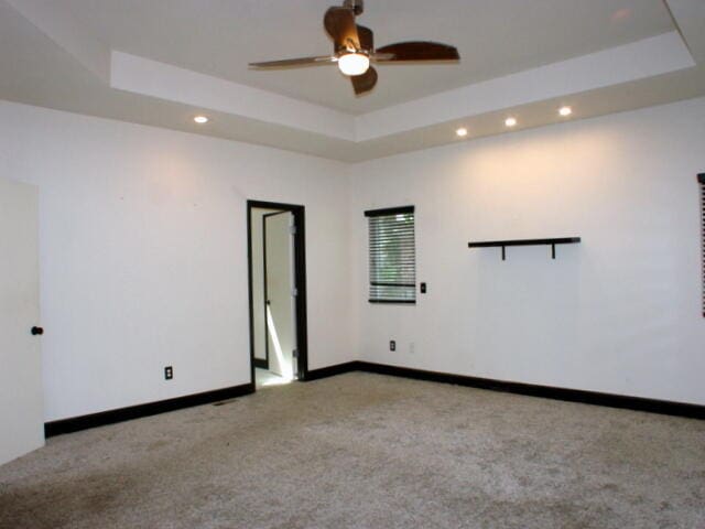 carpeted empty room featuring ceiling fan and a tray ceiling