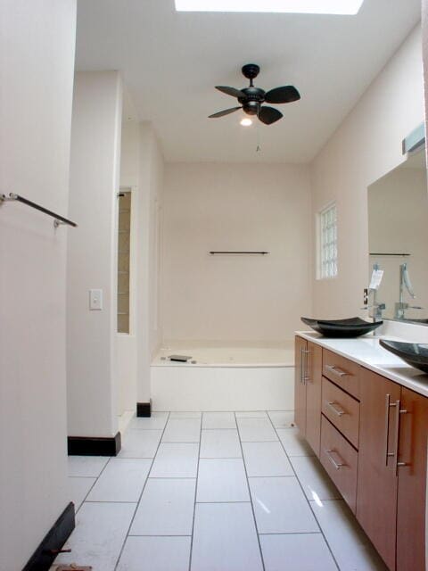 bathroom featuring tile patterned flooring, a tub to relax in, vanity, and ceiling fan