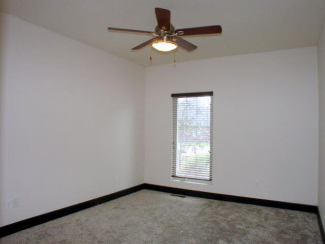 carpeted spare room featuring ceiling fan