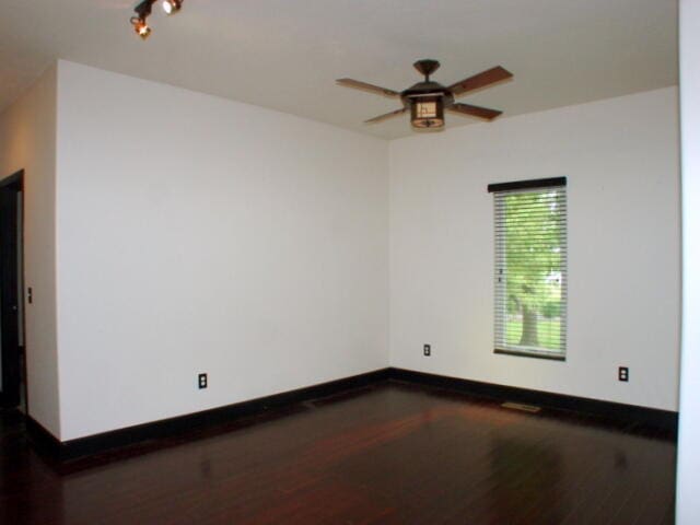 empty room with ceiling fan and dark hardwood / wood-style flooring