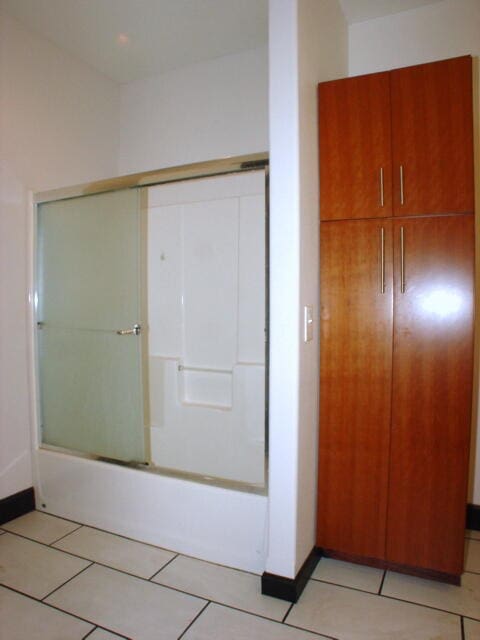 bathroom featuring shower / bath combination with glass door and tile patterned flooring