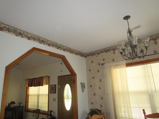 entrance foyer with wallpapered walls, a chandelier, and visible vents