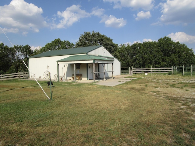rear view of house with fence, metal roof, a yard, and a patio